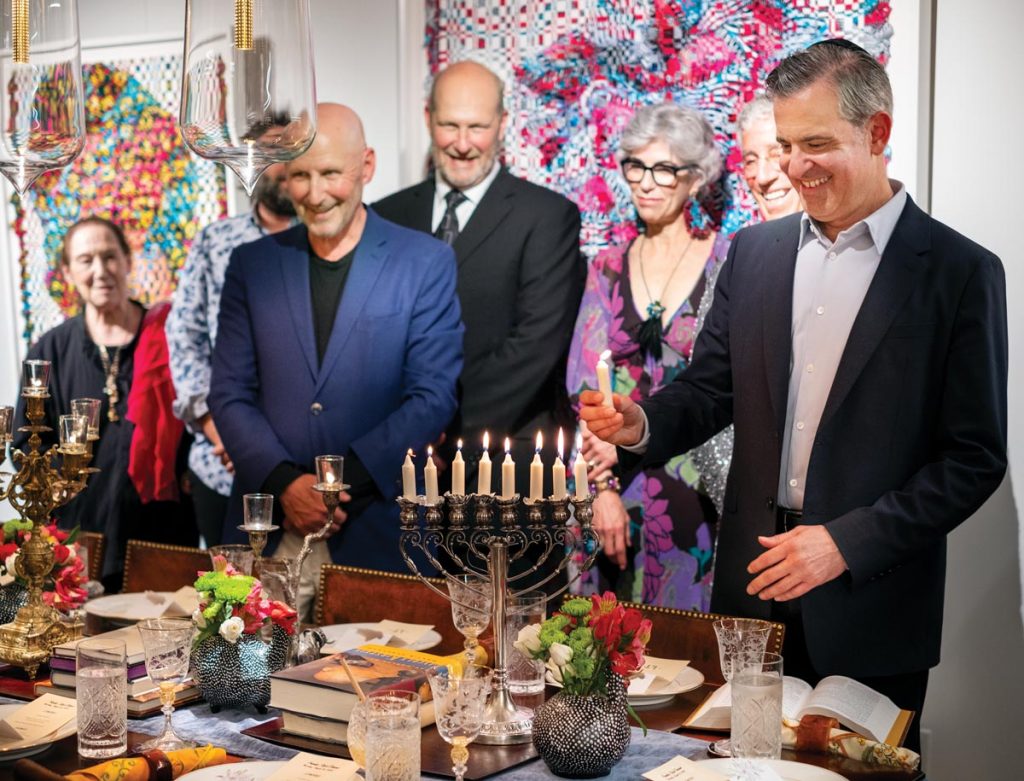 Miami Beach Mayor Steven Meiner recites the holiday prayer and lights the menorah before the start of dinner